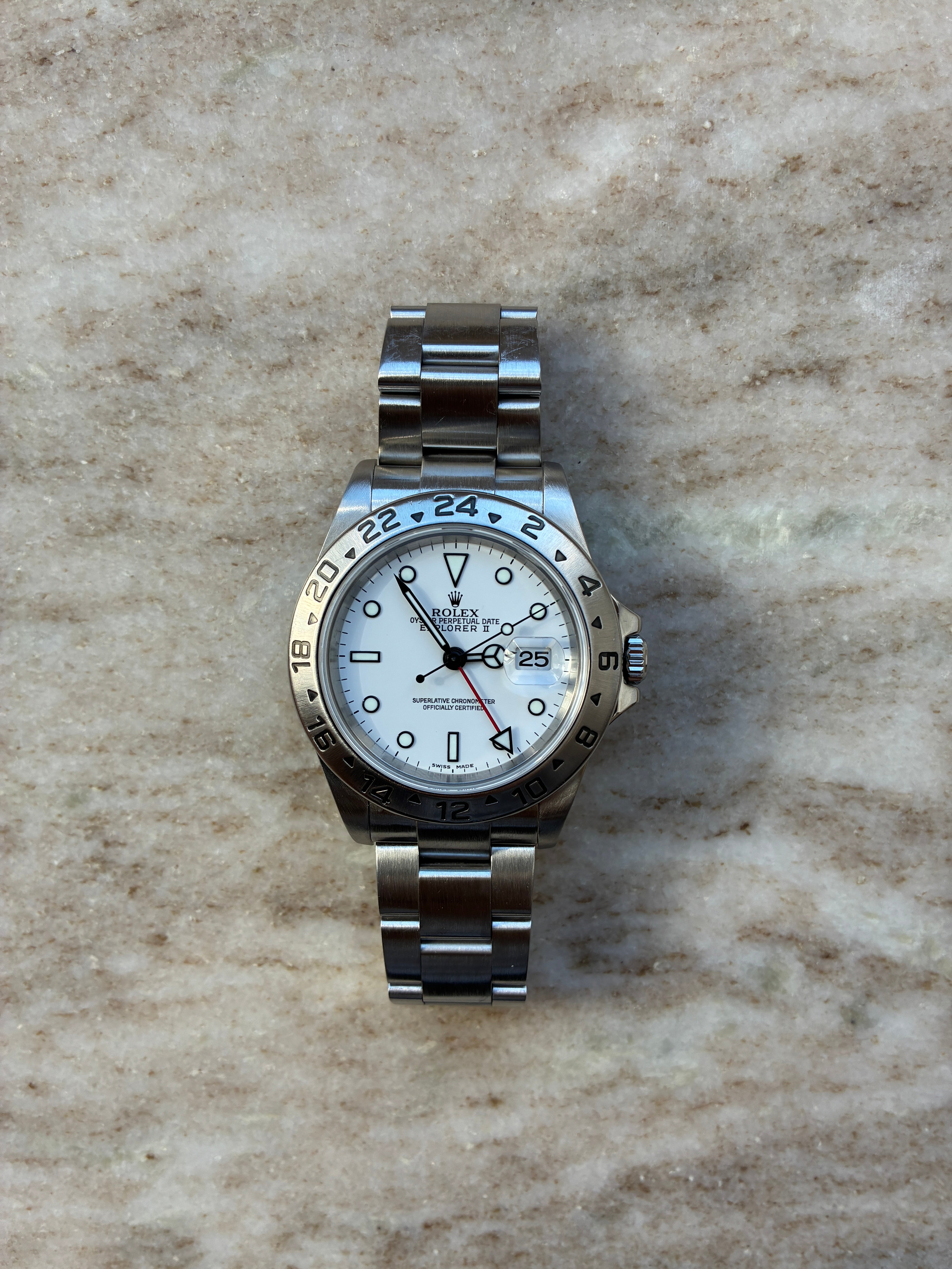 Rolex Explorer II mit weißem Zifferblatt und Stahlarmband auf Marmoruntergrund