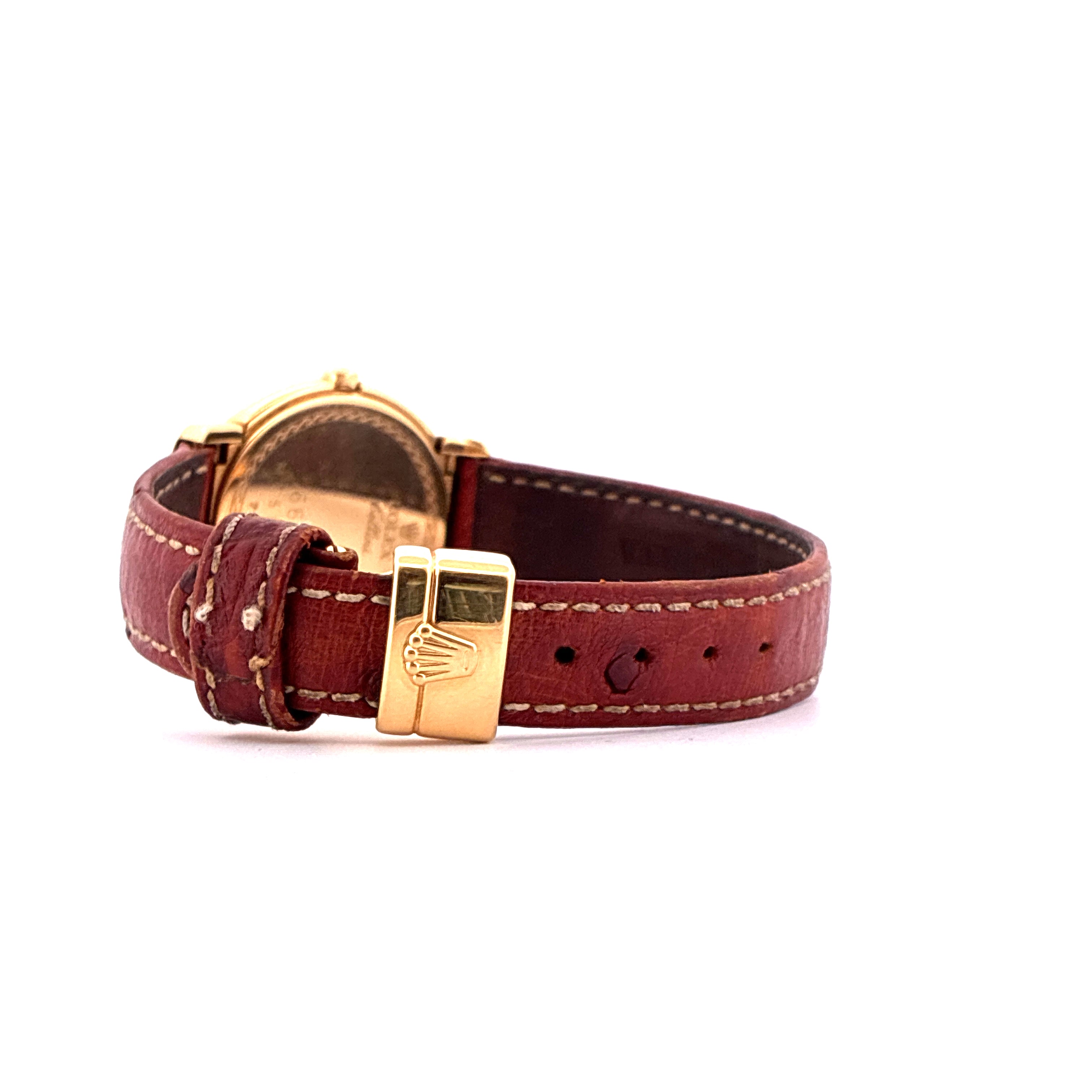 Seitliche Nahaufnahme einer goldfarbenen Rolex Cellini Uhr mit braunem Lederarmband und goldener Schließe