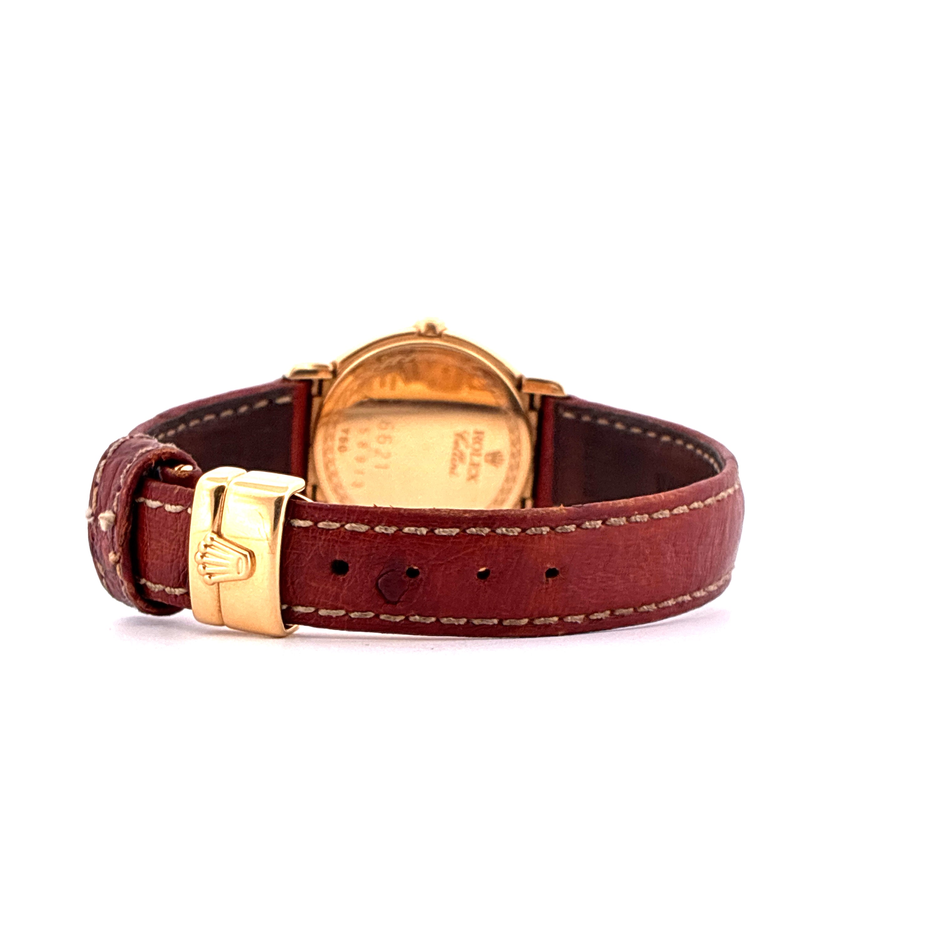Eine goldene Rolex Cellini Uhr mit braunem Lederarmband und goldenem Dornverschluss im Seitenprofil