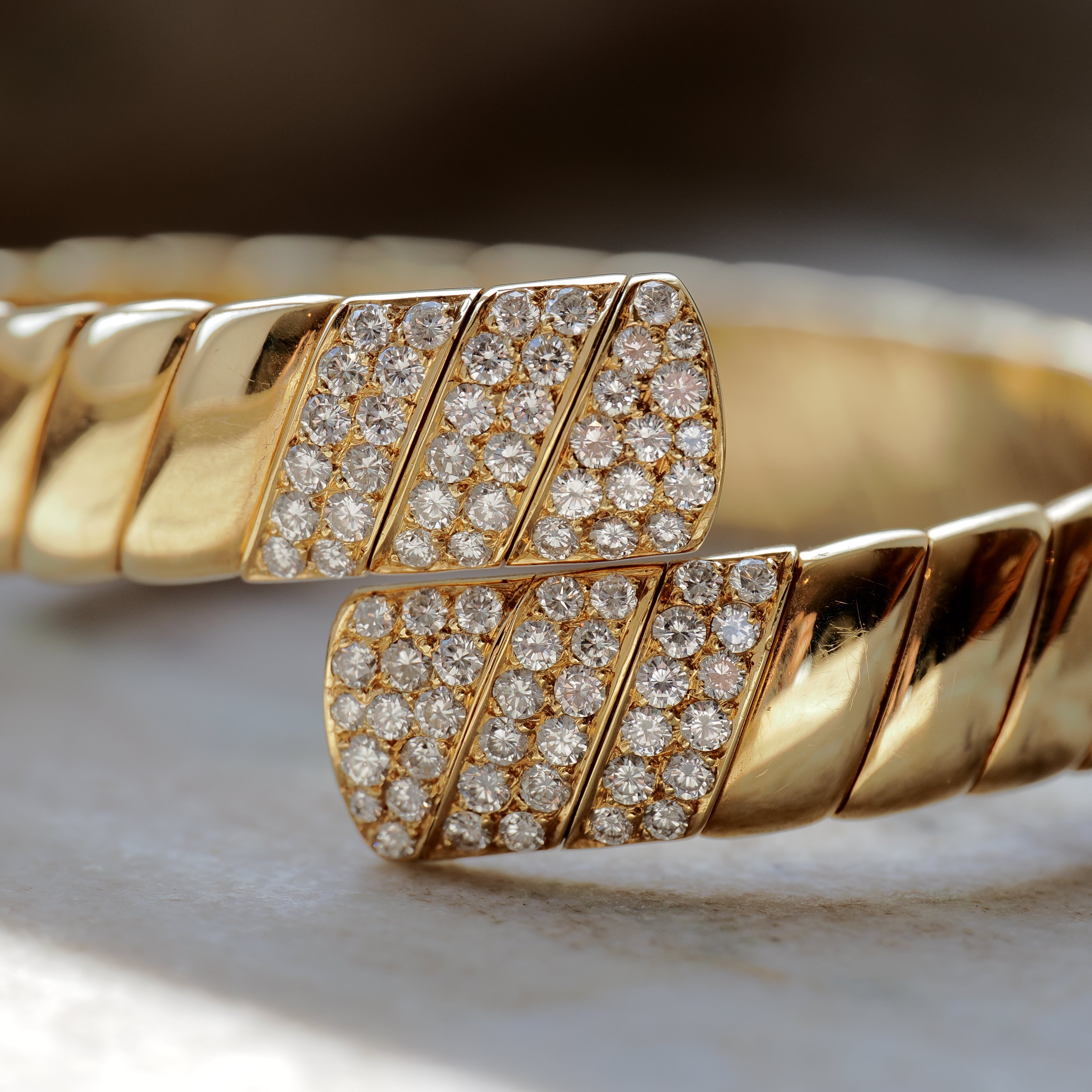 Cartier Vintage Armreif aus 18K Gelbgold mit 106 Brillanten im Na- turlich-Detailaufnahme auf hellem Hintergrund
