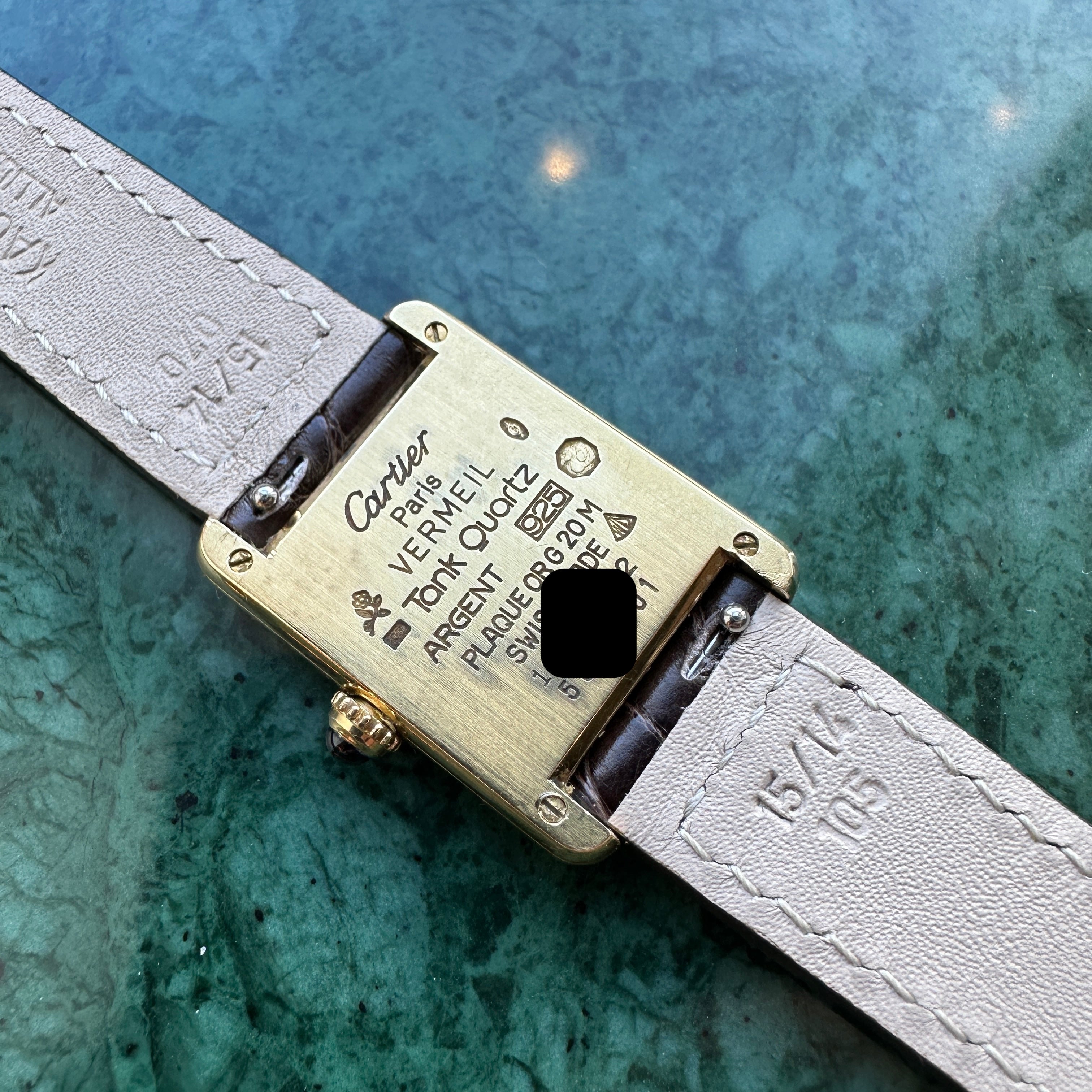 Rückseite einer Cartier Tank Vermeil mit Gravuren und einem hellbeigen Lederarmband