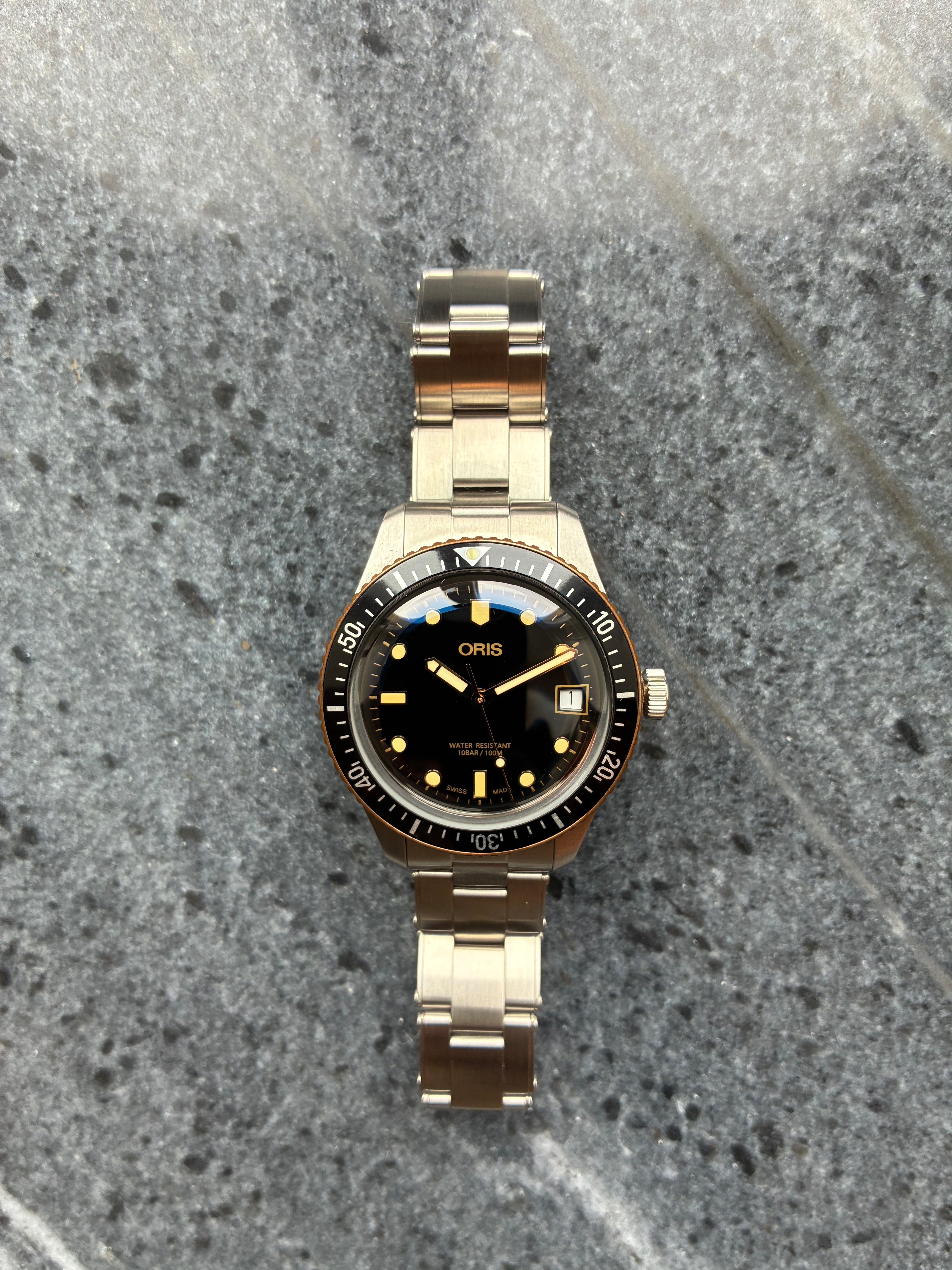 Oris Divers Sixty Five Automatikuhr mit schwarzem Zifferblatt und Edelstahluhrband auf Steingrund