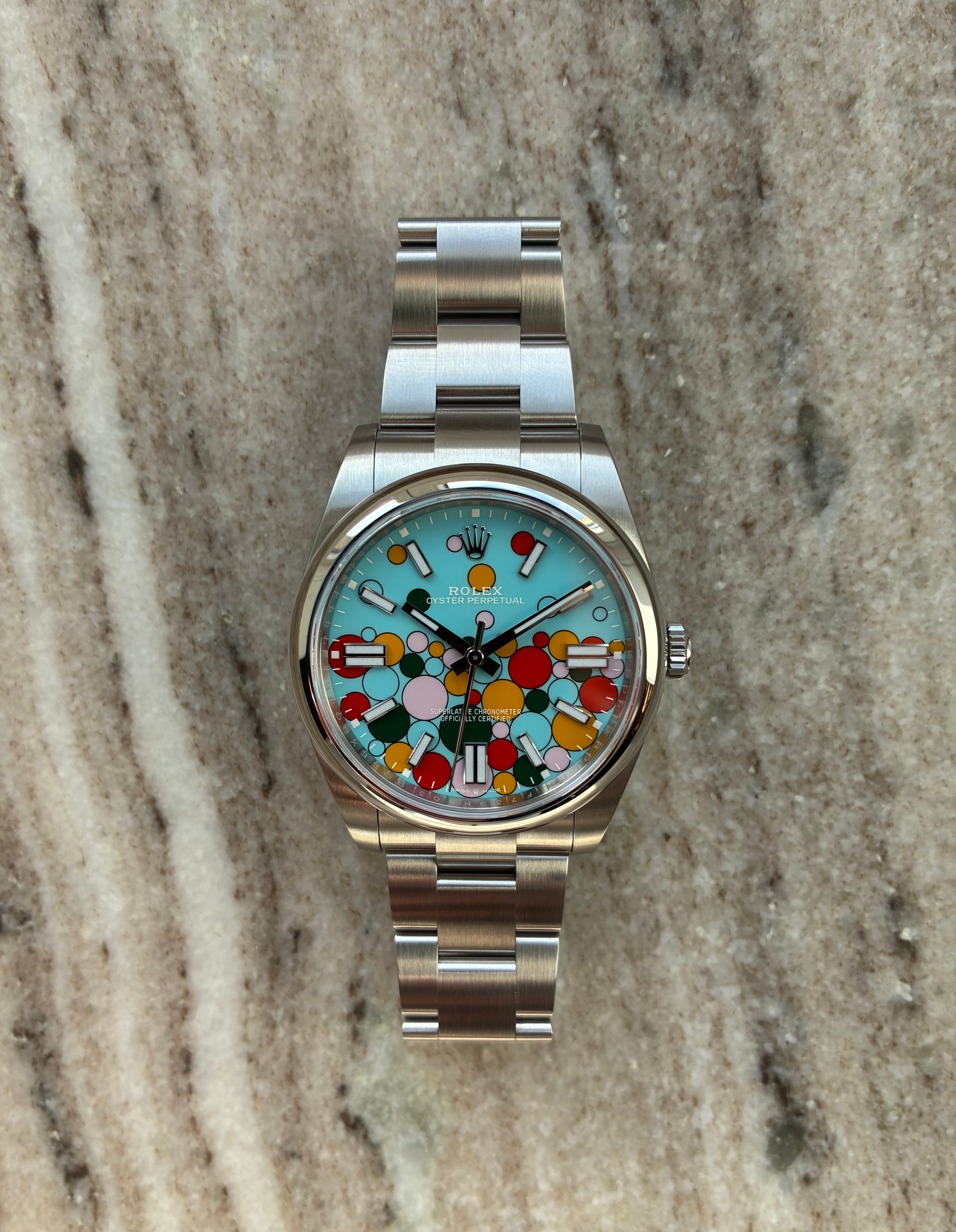 Rolex Oyster Perpetual 41 Celebration mit farbigem Ball-Zifferblatt aus Stahl auf gemustertem Hintergrund