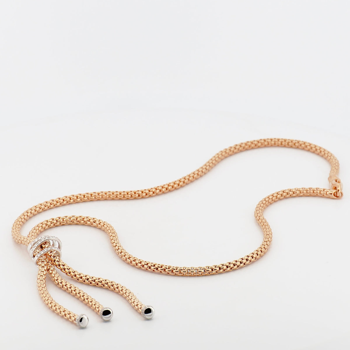 Fope Collier Prima in Roségold mit feingliedriger Kette, verziertem Schieberelement und Quasten-Enden auf weißem Hintergrund